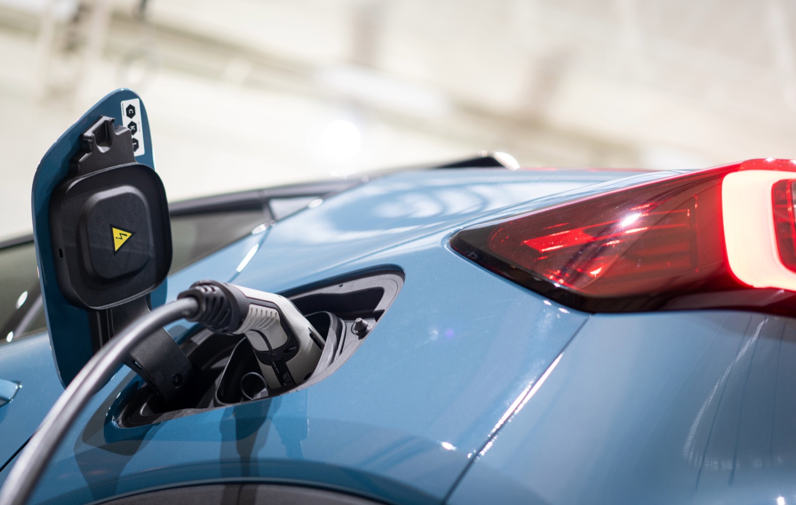 A charging cable connected to the port of a blue electric vehicle